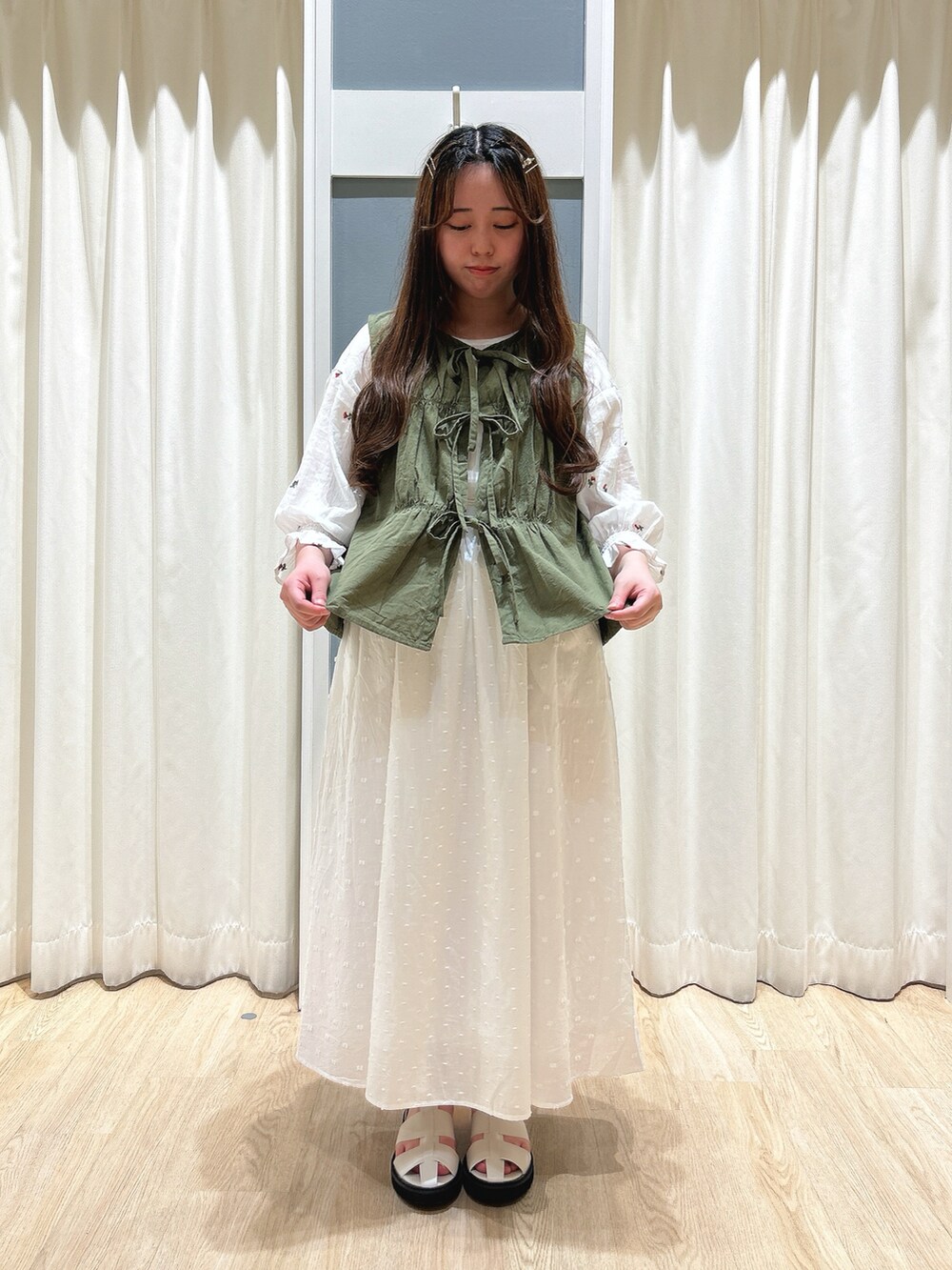 グリーン系のベスト、ホワイト系のスカート、ホワイト系のハンドバッグを着用したレディースの夏コーディネートの4枚目の写真