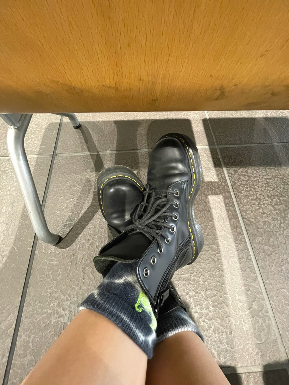 グレー系のデニムパンツ、ブラック系のブーツ、ホワイト系のショルダーバッグを着用したレディースの秋コーディネートの2枚目の写真