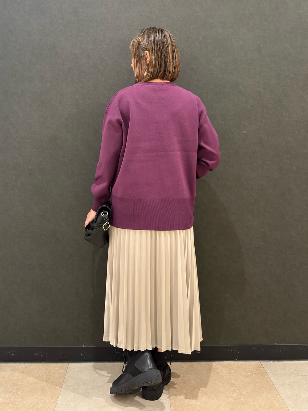 ブラック系のブーツ、ブラック系のショルダーバッグ、ベージュ系のスカートを着用したレディースの秋コーディネートの3枚目の写真