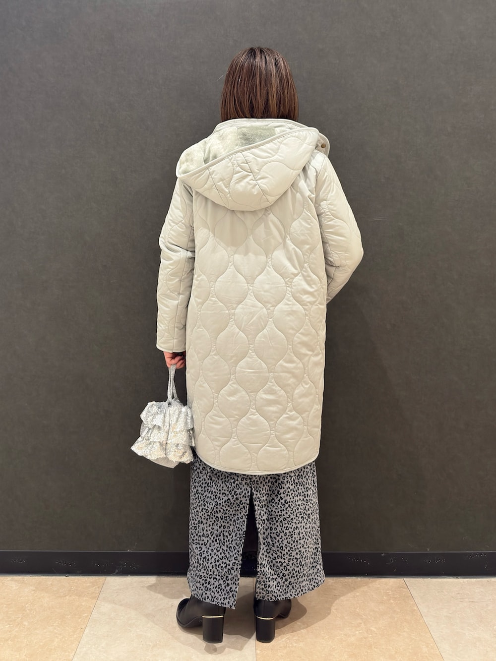 ブラック系のブーツ、シルバー系のショルダーバッグ、グレー系のスカートを着用したレディースの冬コーディネートの3枚目の写真