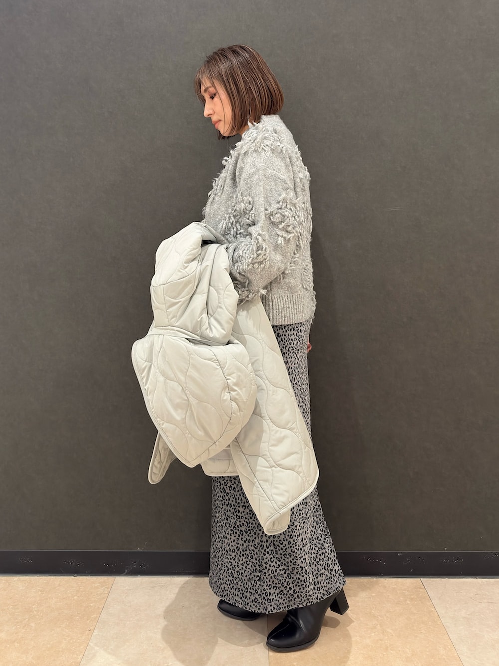 ブラック系のブーツ、シルバー系のショルダーバッグ、グレー系のスカートを着用したレディースの冬コーディネートの6枚目の写真