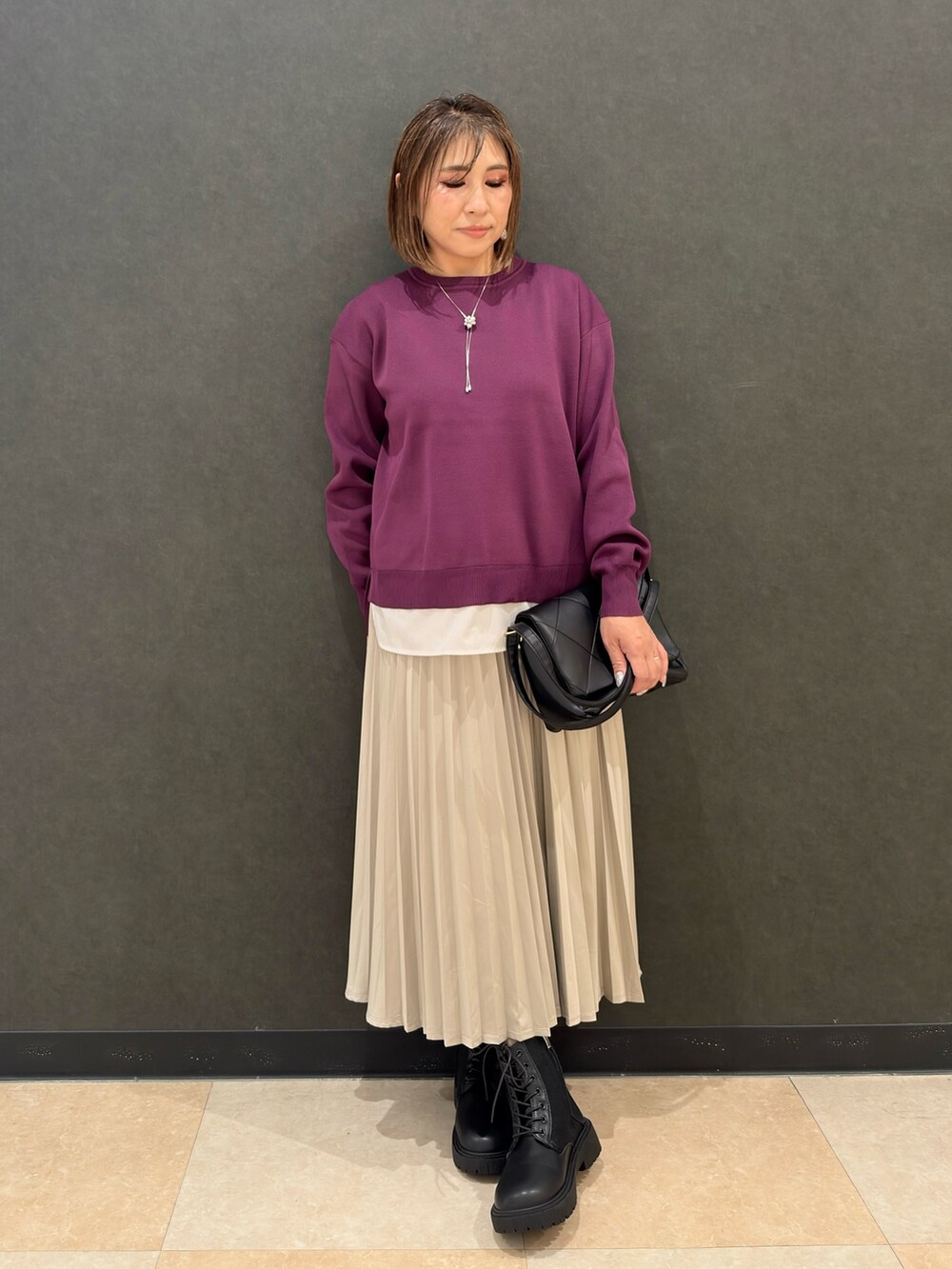 ブラック系のブーツ、ブラック系のショルダーバッグ、ベージュ系のスカートを着用したレディースの秋コーディネートの4枚目の写真