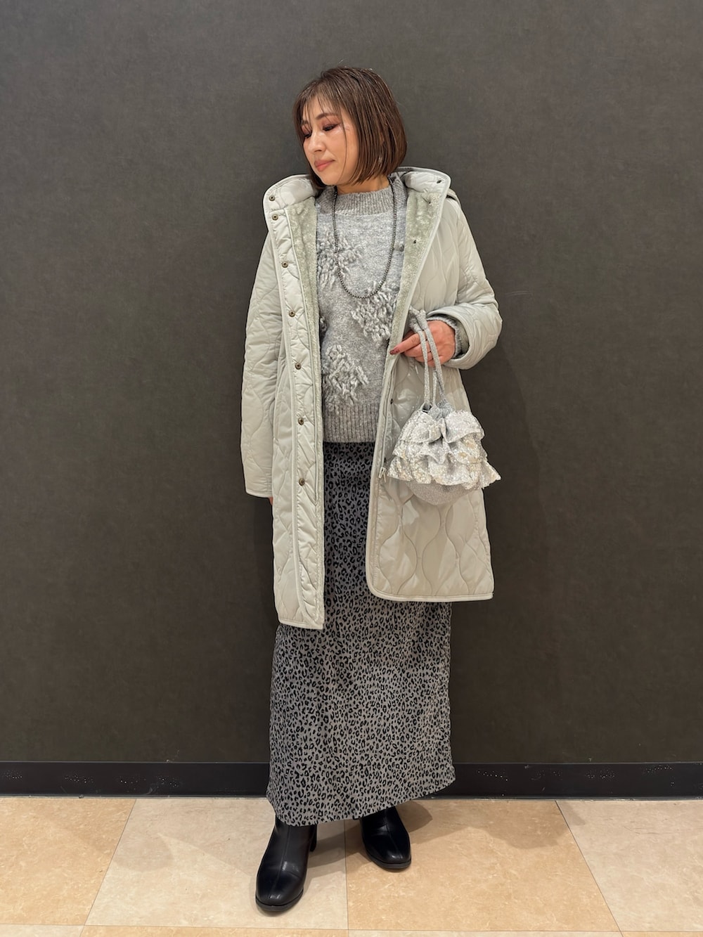 ブラック系のブーツ、シルバー系のショルダーバッグ、グレー系のスカートを着用したレディースの冬コーディネートの4枚目の写真