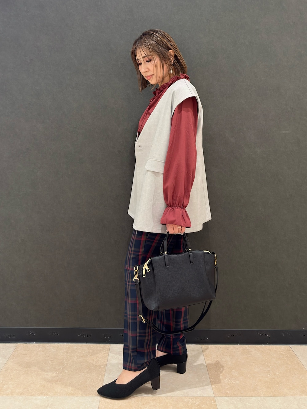 グレー系のベスト、レッド系のシャツ/ブラウス、ブルー系のその他パンツを着用したレディースの秋コーディネートの2枚目の写真