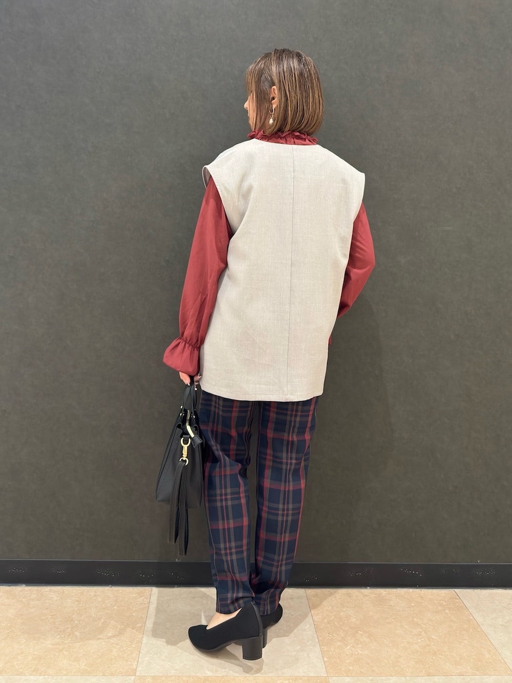 グレー系のベスト、レッド系のシャツ/ブラウス、ブルー系のその他パンツを着用したレディースの秋コーディネートの3枚目の写真