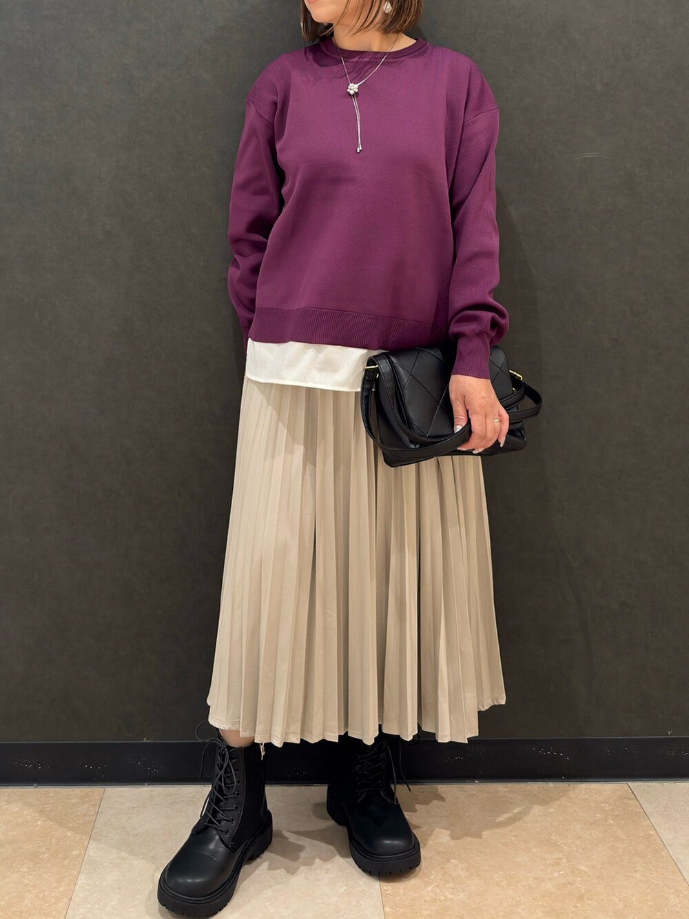 ブラック系のブーツ、ブラック系のショルダーバッグ、ベージュ系のスカートを着用したレディースの秋コーディネートの5枚目の写真