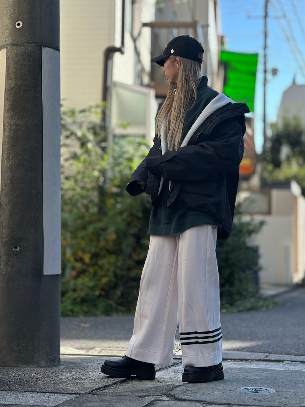 ブラック系のマウンテンパーカー、ホワイト系のスウェットパンツ、ブラック系のローファーを着用したレディースの秋コーディネートの2枚目の写真