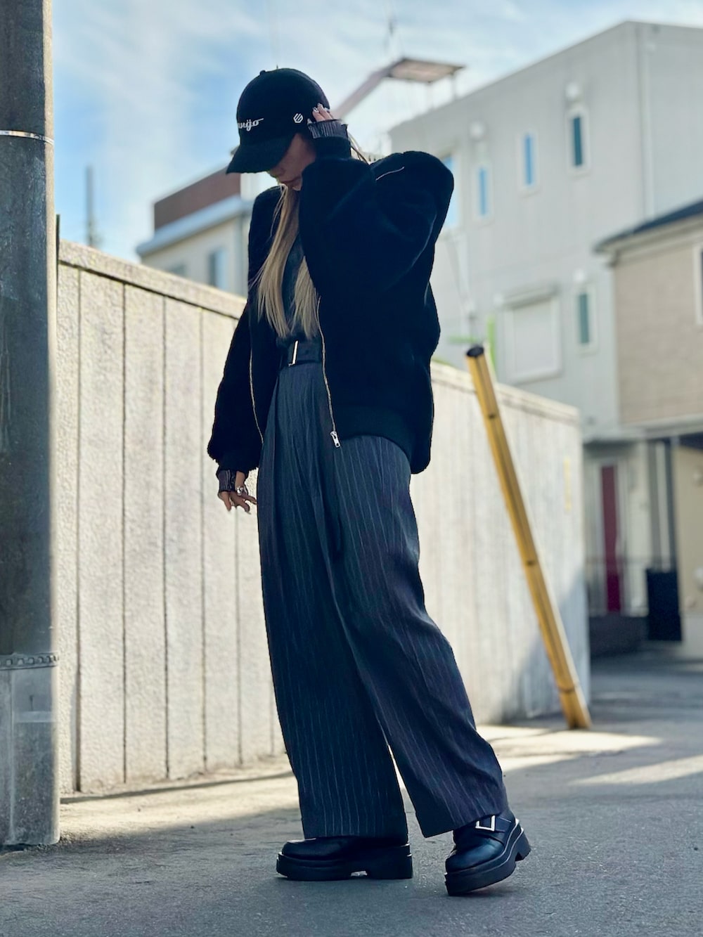 グレー系のパンツ、ブラック系のローファー、ブラック系のブルゾンを着用したレディースの冬コーディネートの4枚目の写真