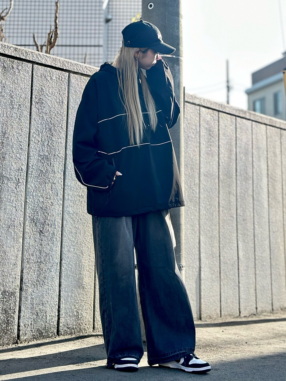 ブラック系のデニムパンツ、ホワイト系のスニーカー、ブラック系のトップスを着用したレディースの冬コーディネートの2枚目の写真