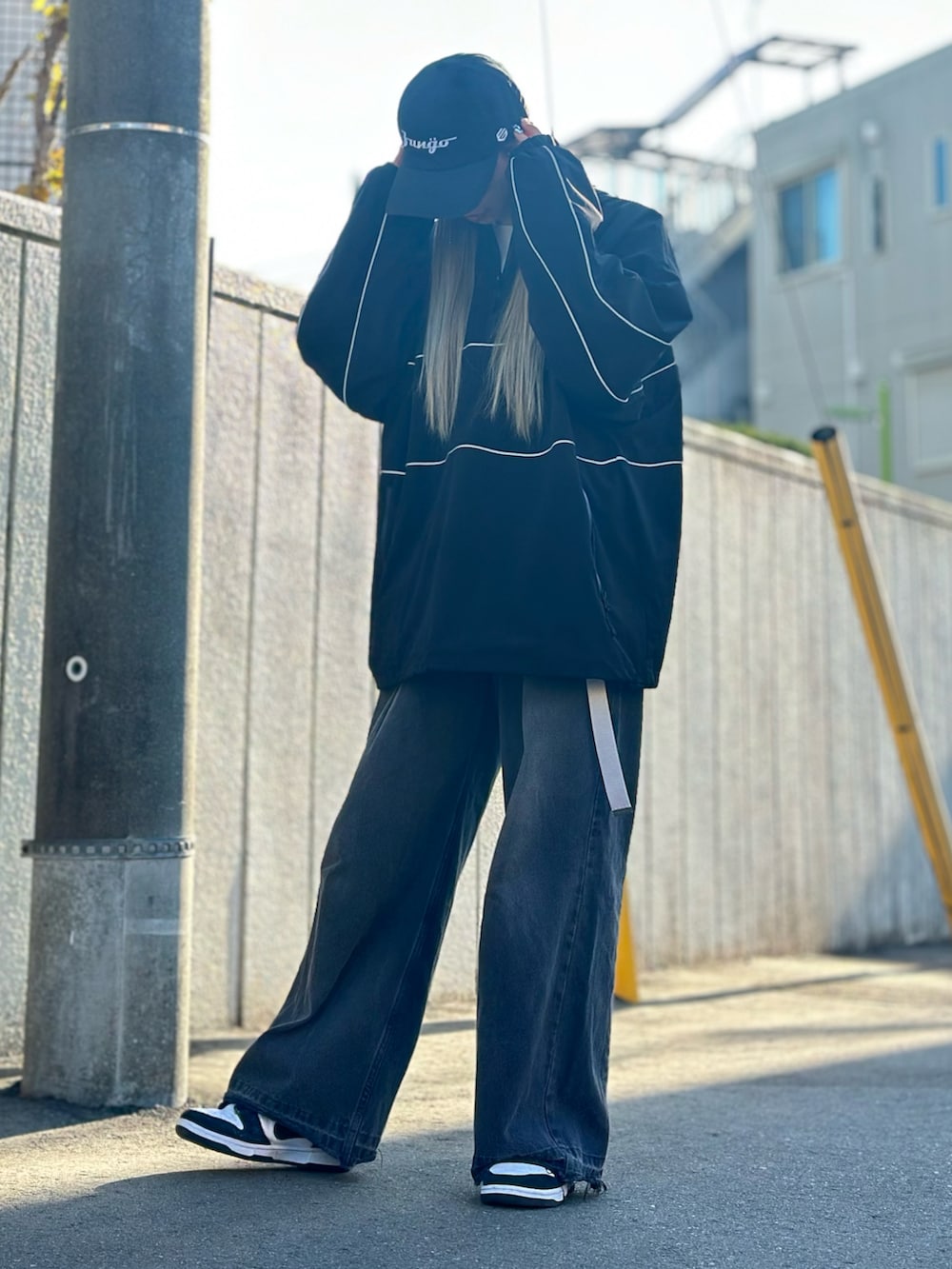 ブラック系のデニムパンツ、ホワイト系のスニーカー、ブラック系のトップスを着用したレディースの冬コーディネートの4枚目の写真