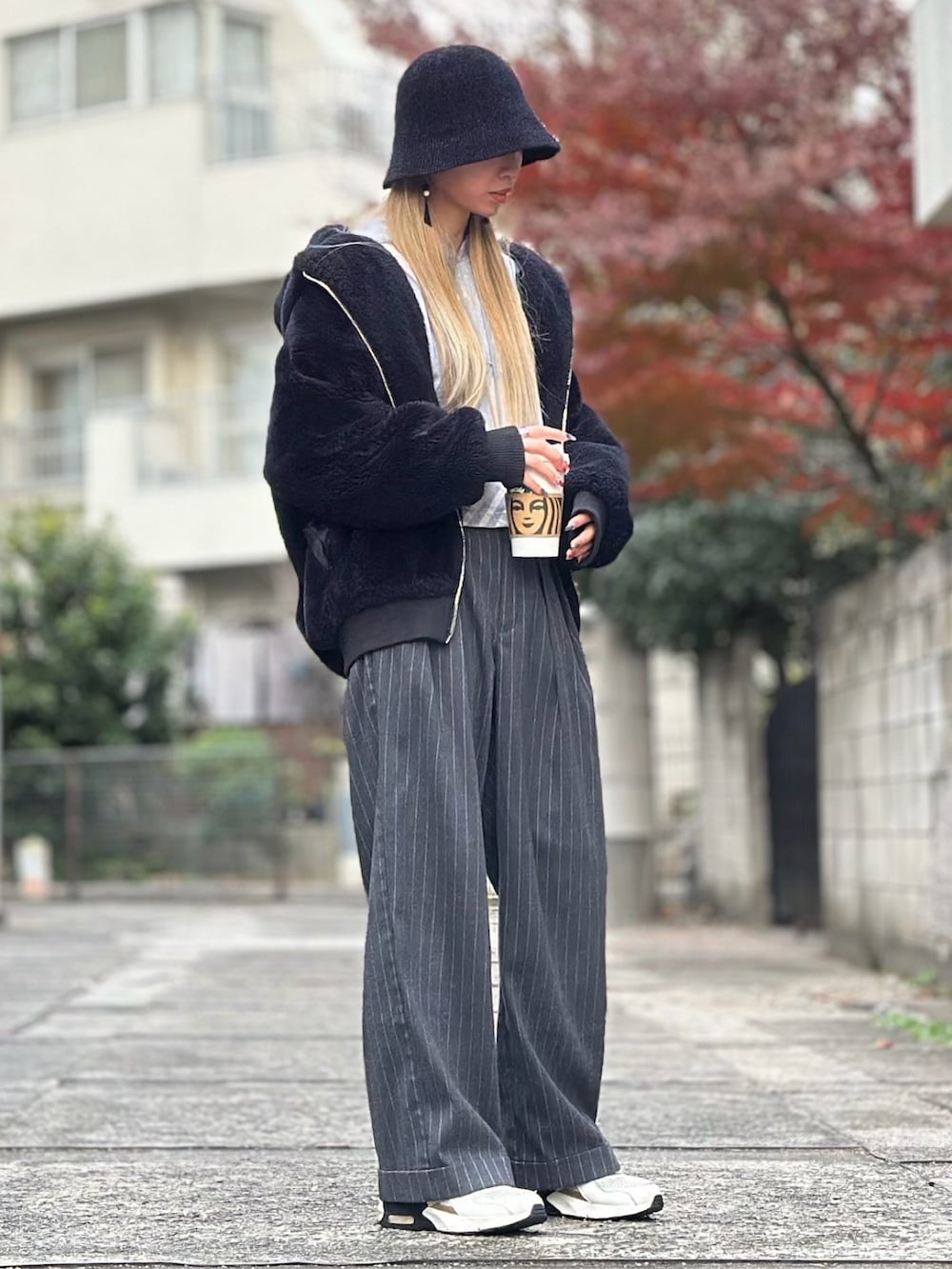 ブラック系のブルゾン、グレー系のパンツ、ベージュ系のスニーカーを着用したレディースの冬コーディネートの2枚目の写真