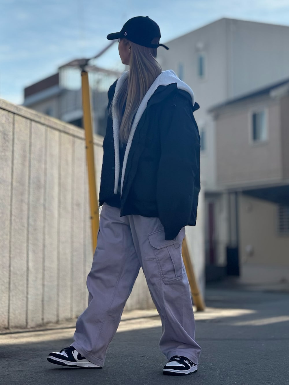 ブラック系のマウンテンパーカー、ブルー系のニット/セーター、パープル系のカーゴパンツを着用したレディースの冬コーディネートの2枚目の写真