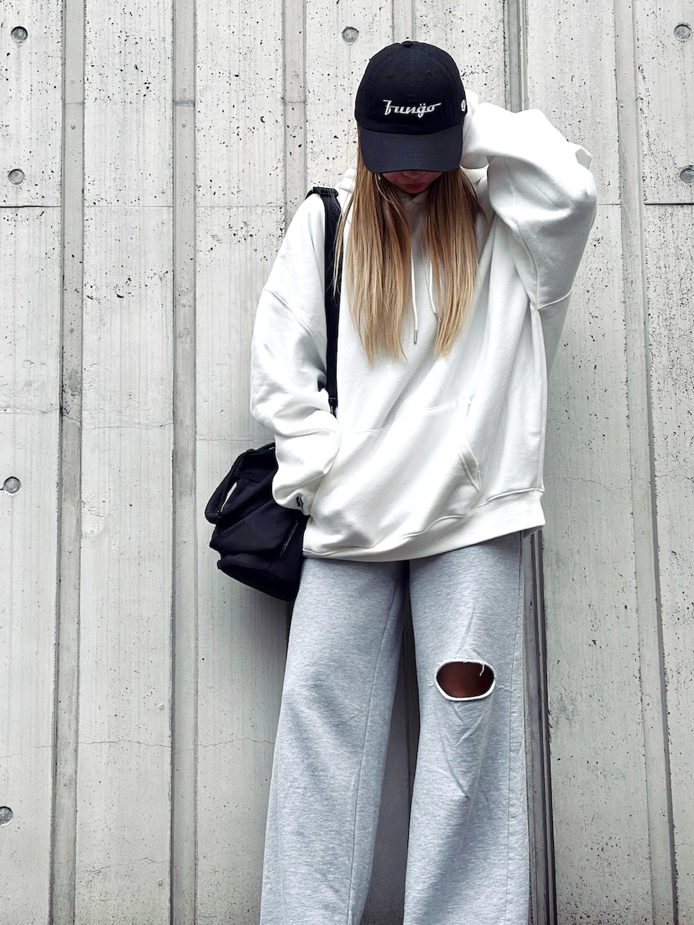 ブラック系のショルダーバッグ、ホワイト系のパーカー、グレー系のパンツを着用したレディースの冬コーディネートの2枚目の写真