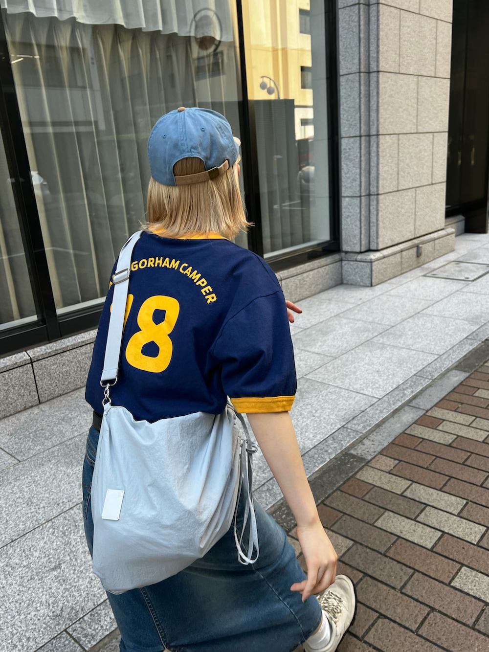 ベージュ系のスニーカー、ブルー系のデニムスカート、ブルー系のTシャツ/カットソーを着用したレディースの夏コーディネートの2枚目の写真