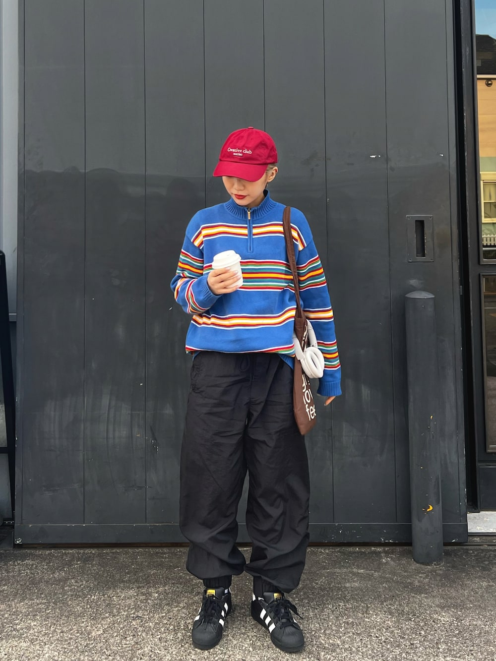 ブラック系のその他パンツ、ホワイト系のスニーカー、ブラウン系のトートバッグを着用したレディースの冬コーディネートの2枚目の写真