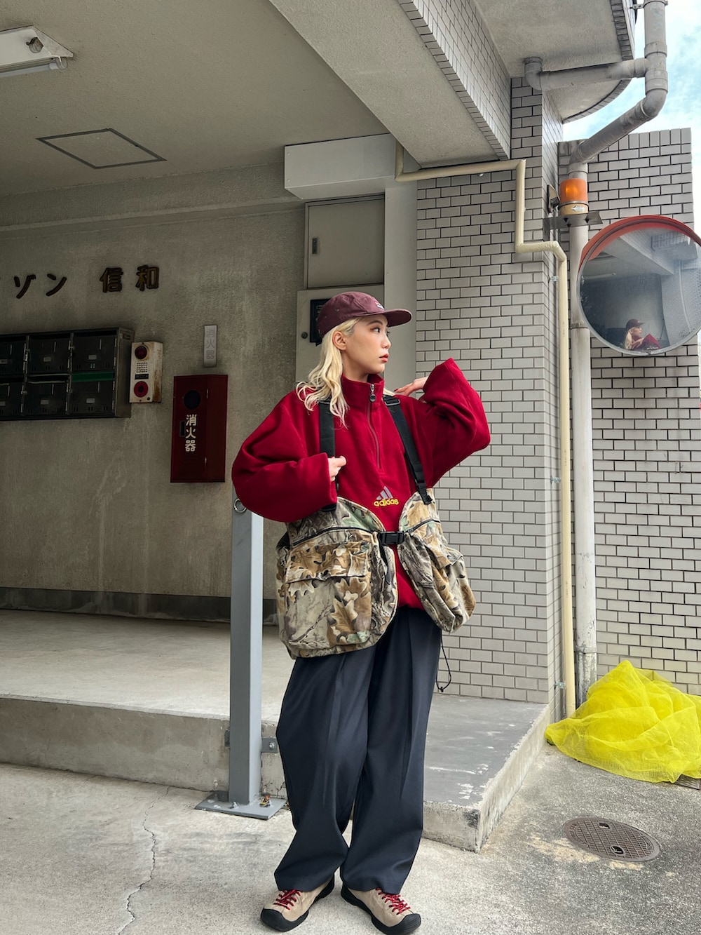 グレー系のスラックス、ベージュ系のスニーカー、ブラウン系のキャップを着用したレディースの冬コーディネートの2枚目の写真