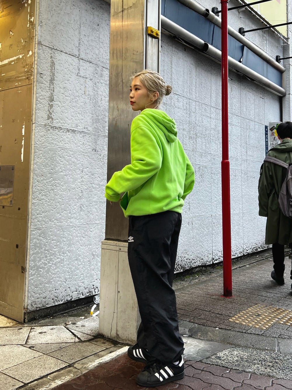 グリーン系のパーカー、ブラック系のその他パンツ、ホワイト系のスニーカーを着用したレディースの冬コーディネートの2枚目の写真