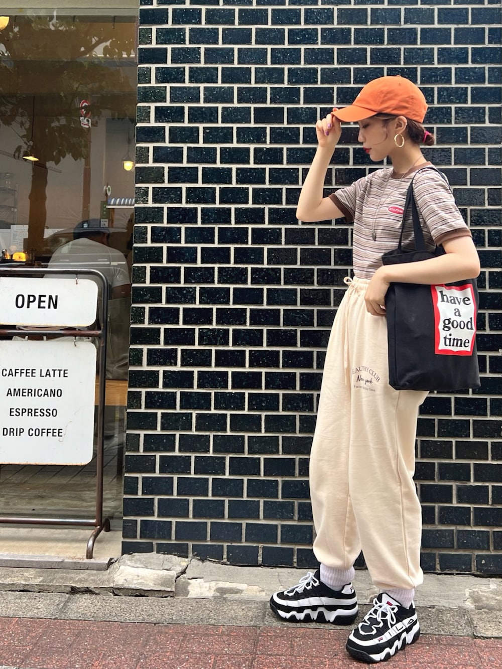 ブラック系のトートバッグ、ベージュ系のスウェットパンツ、ブラック系のスニーカーを着用したレディースの夏コーディネートの2枚目の写真