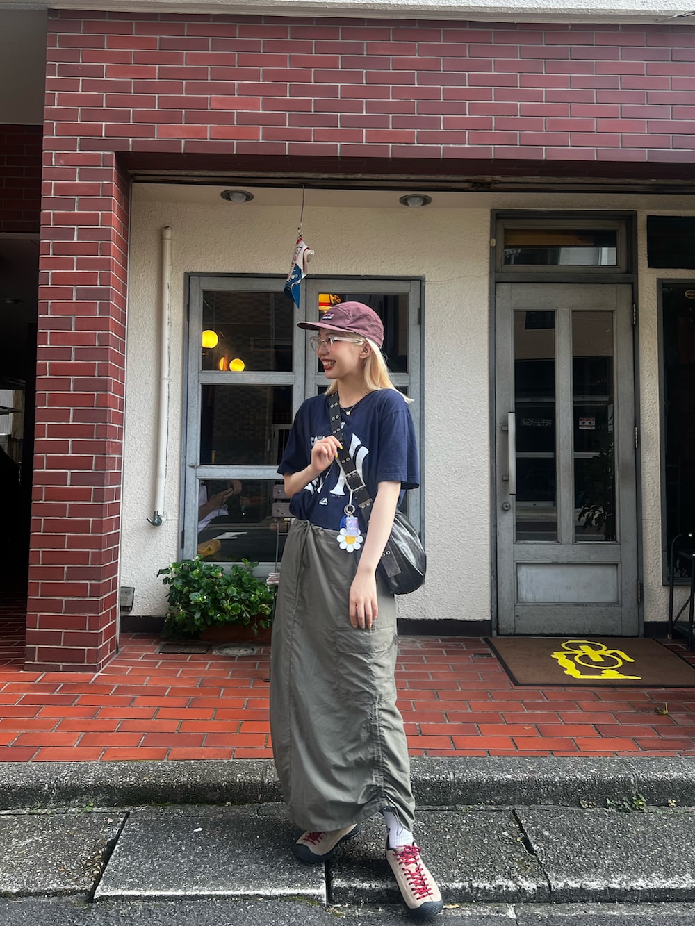 ベージュ系のスニーカー、グリーン系のスカート、ブラウン系のショルダーバッグを着用したレディースの夏コーディネートの2枚目の写真