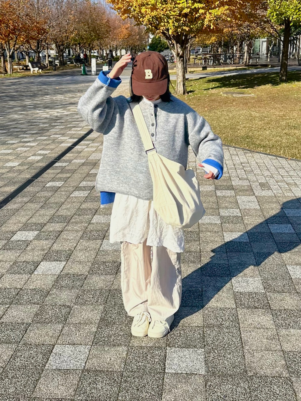 グレー系のニット/セーター、ホワイト系のショルダーバッグ、ホワイト系のワンピース/ドレスを着用したレディースの秋コーディネートの2枚目の写真