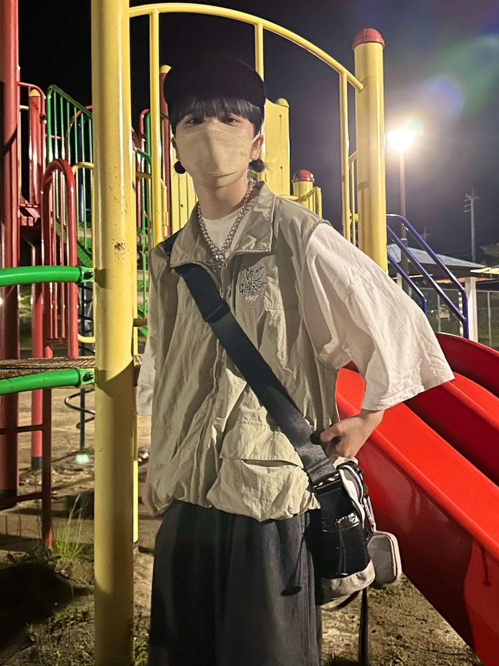 ベージュ系のベスト、ホワイト系のメッセンジャーバッグ、ブラック系のデニムパンツを着用したレディースの春コーディネートの2枚目の写真