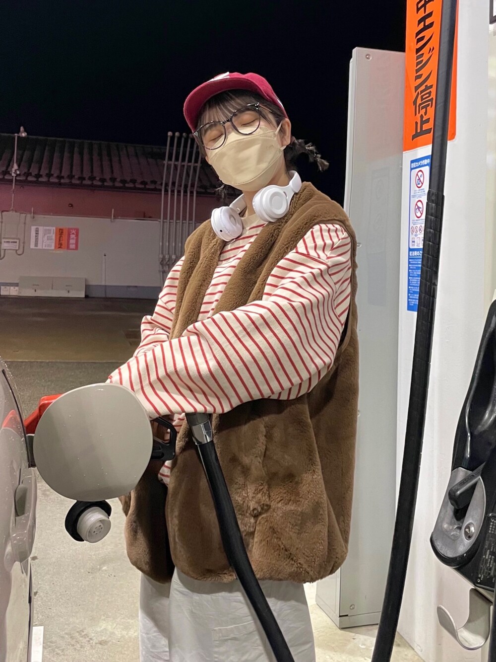 ブラウン系のベスト、レッド系のスウェット、ホワイト系のチノパンツを着用したレディースの冬コーディネートの2枚目の写真