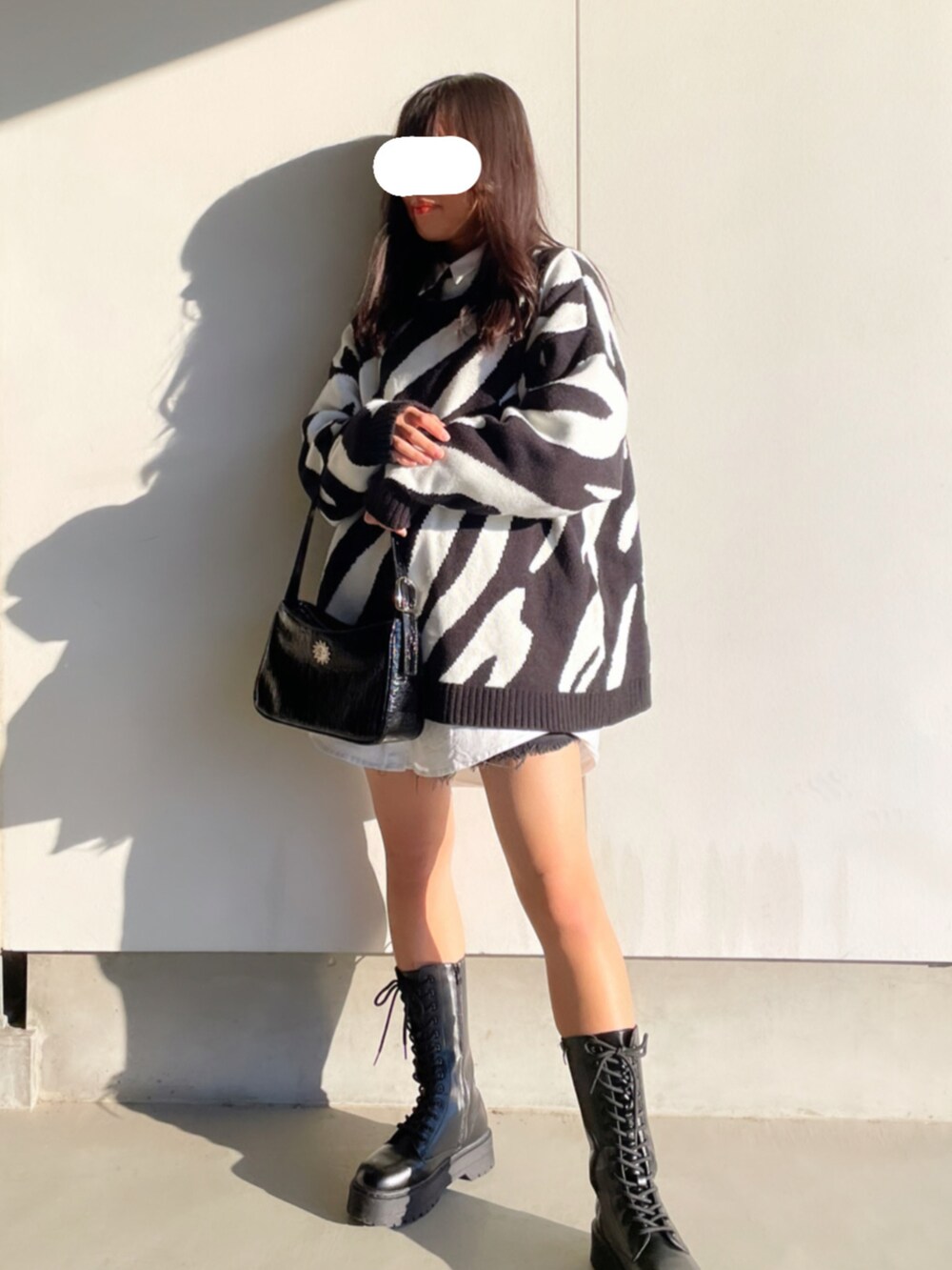 ブラック系のニット/セーター、ブラック系のショルダーバッグ、ホワイト系のシャツ/ブラウスを着用したレディースの秋コーディネートの2枚目の写真