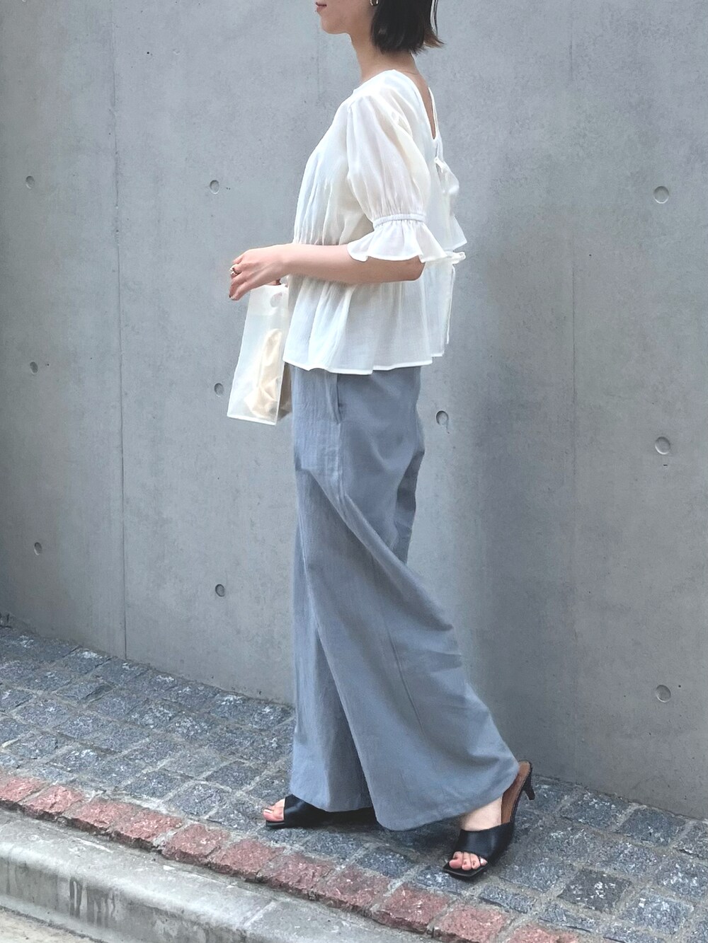 ブルー系のつなぎ/オールインワン、ブラック系のサンダル、ホワイト系のバッグを着用したレディースの春コーディネートの2枚目の写真