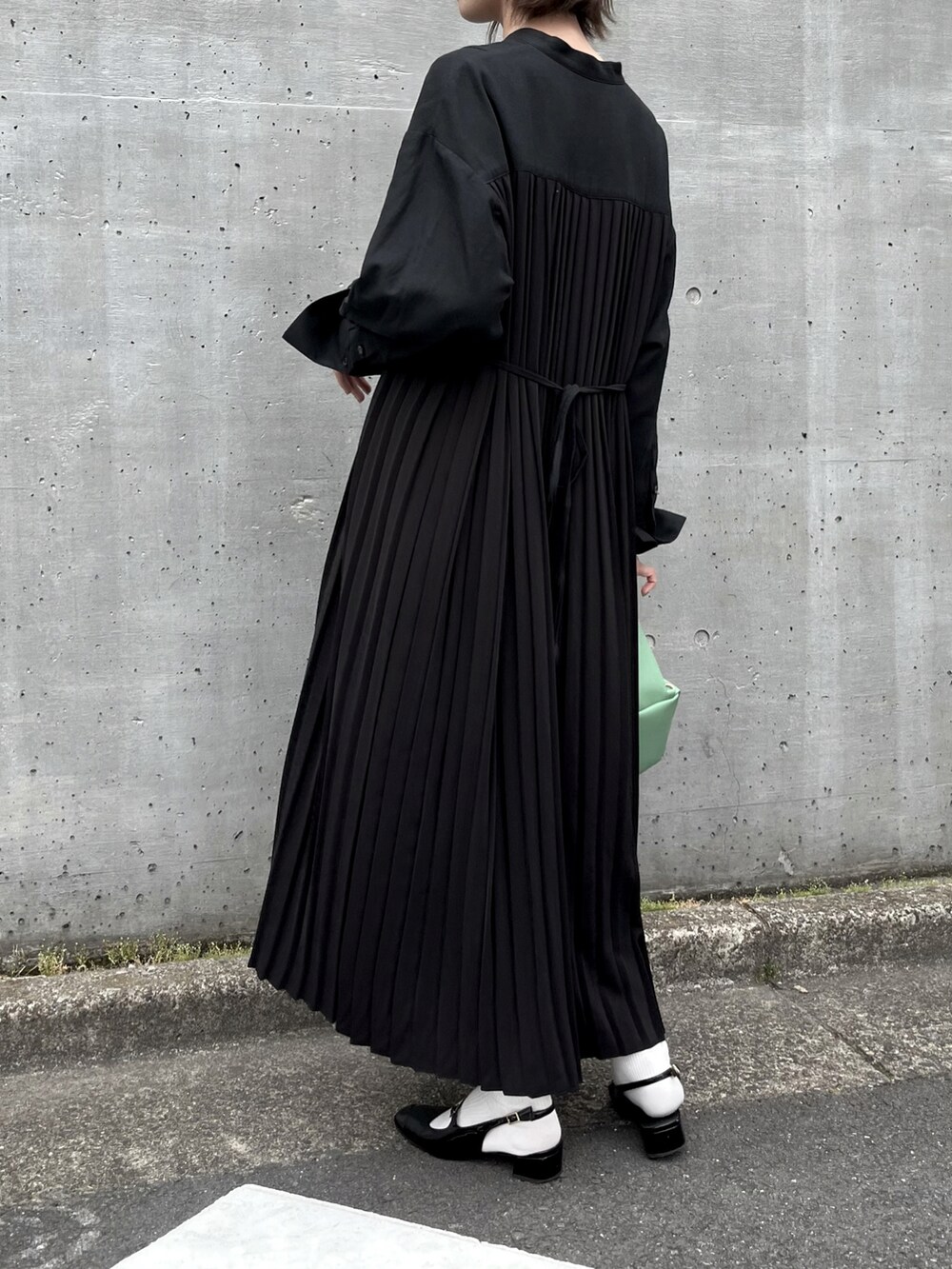 ブラック系のパンプス、ブラック系のワンピース/ドレス、グリーン系のショルダーバッグを着用したレディースの夏コーディネートの3枚目の写真