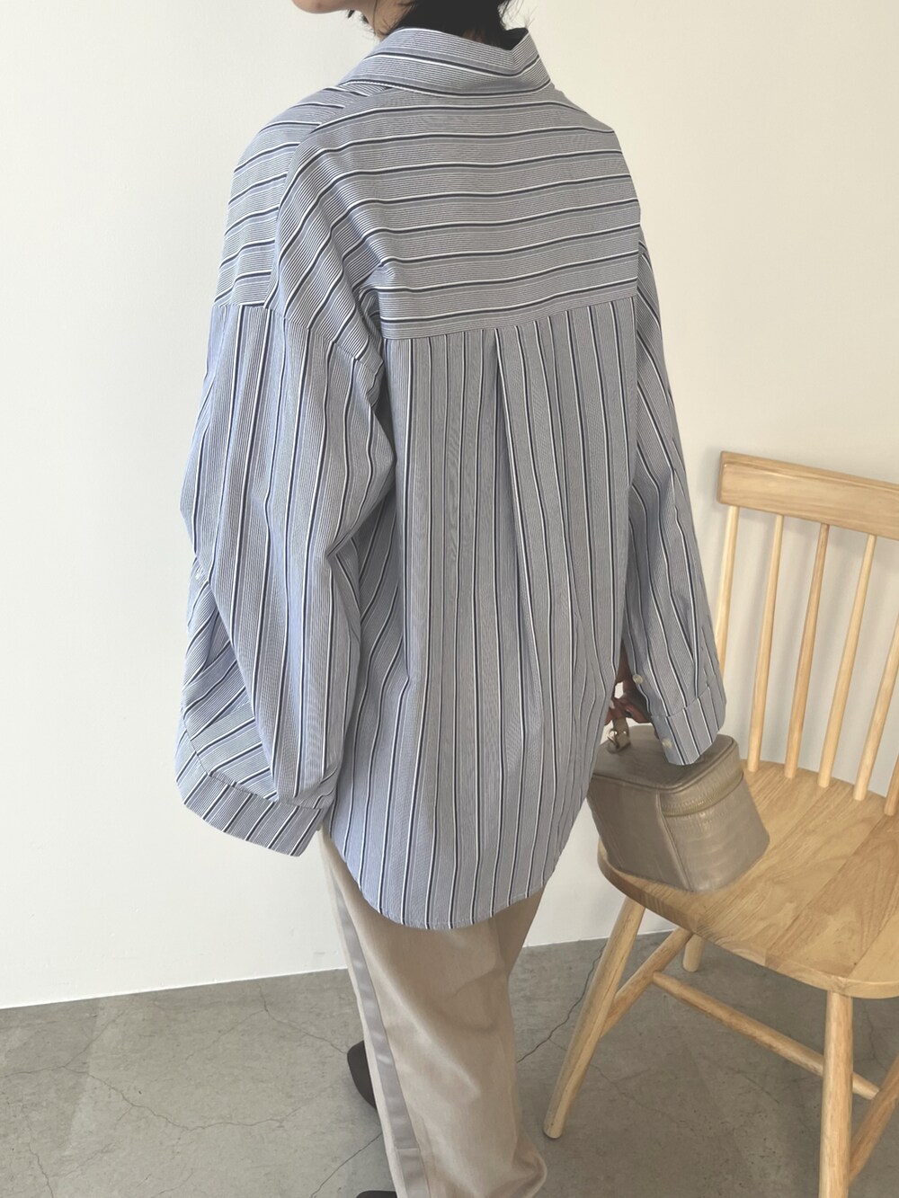 ベージュ系のハンドバッグ、ブルー系のシャツ/ブラウス、ベージュ系のパンツを着用したレディースの秋コーディネートの3枚目の写真