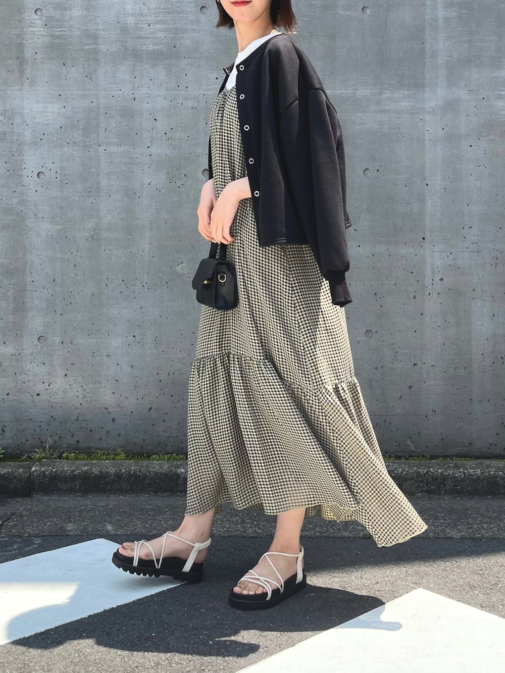ホワイト系のサンダル、イエロー系のワンピース、ブラック系のカーディガン/ボレロを着用したレディースの春コーディネートの2枚目の写真