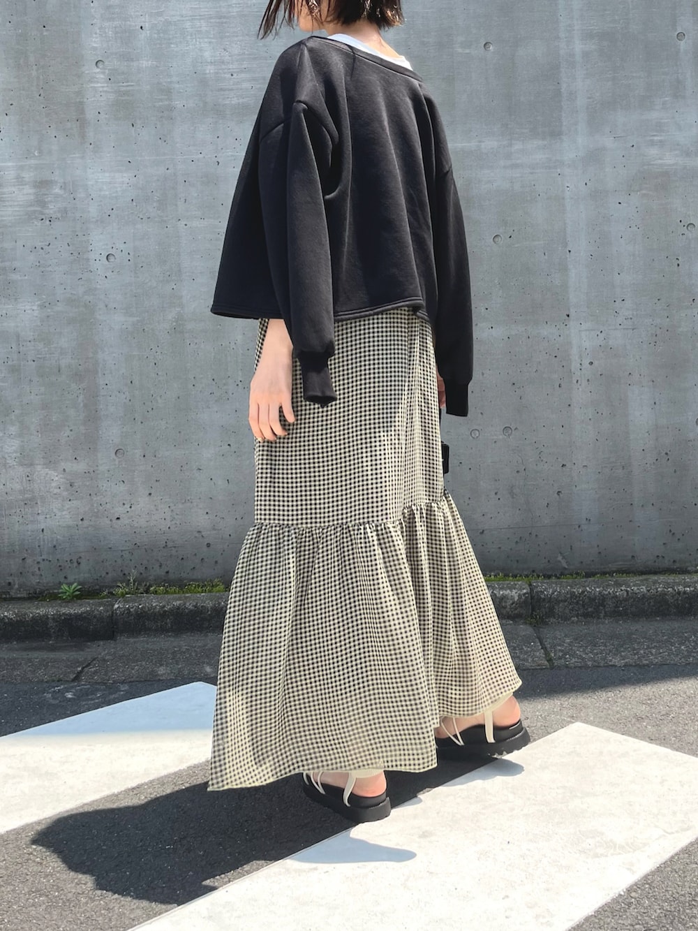 ホワイト系のサンダル、イエロー系のワンピース、ブラック系のカーディガン/ボレロを着用したレディースの春コーディネートの3枚目の写真