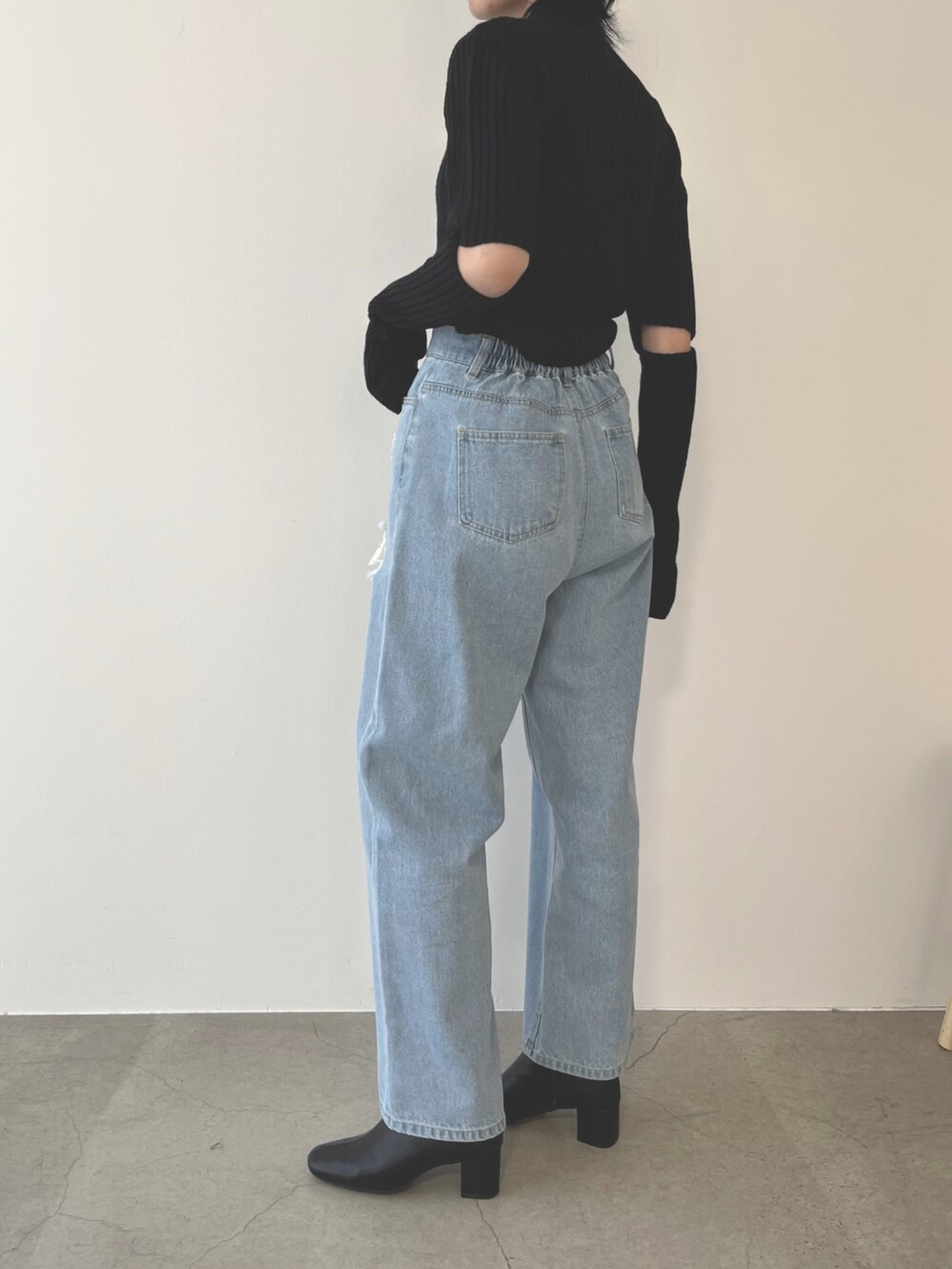 ブラック系のブーツ、ブルー系のデニムパンツ、ブラック系のニット/セーターを着用したレディースの夏コーディネートの2枚目の写真