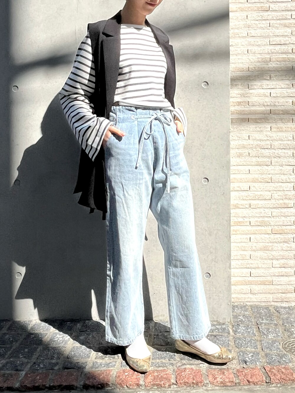 ゴールド系のシューズ、ブラック系のベスト、ブルー系のその他パンツを着用したレディースの冬コーディネートの2枚目の写真