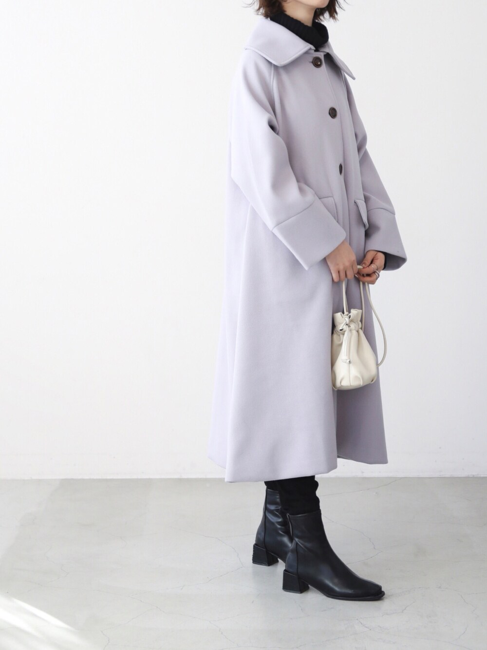 パープル系のステンカラーコート、ブラック系のブーツを着用したレディースの冬コーディネートの2枚目の写真