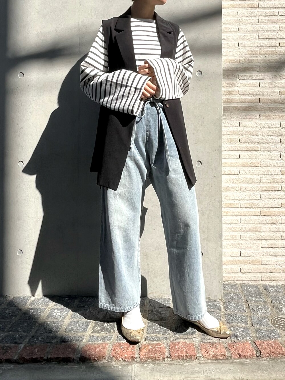 ゴールド系のシューズ、ブラック系のベスト、ブルー系のその他パンツを着用したレディースの冬コーディネートの3枚目の写真