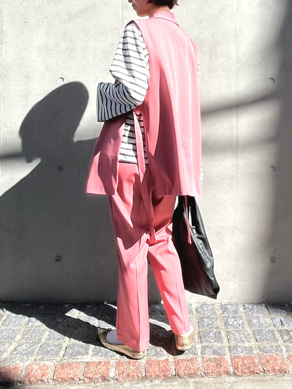 ブラック系のショルダーバッグ、ゴールド系のシューズ、ピンク系のスラックスを着用したレディースの冬コーディネートの2枚目の写真