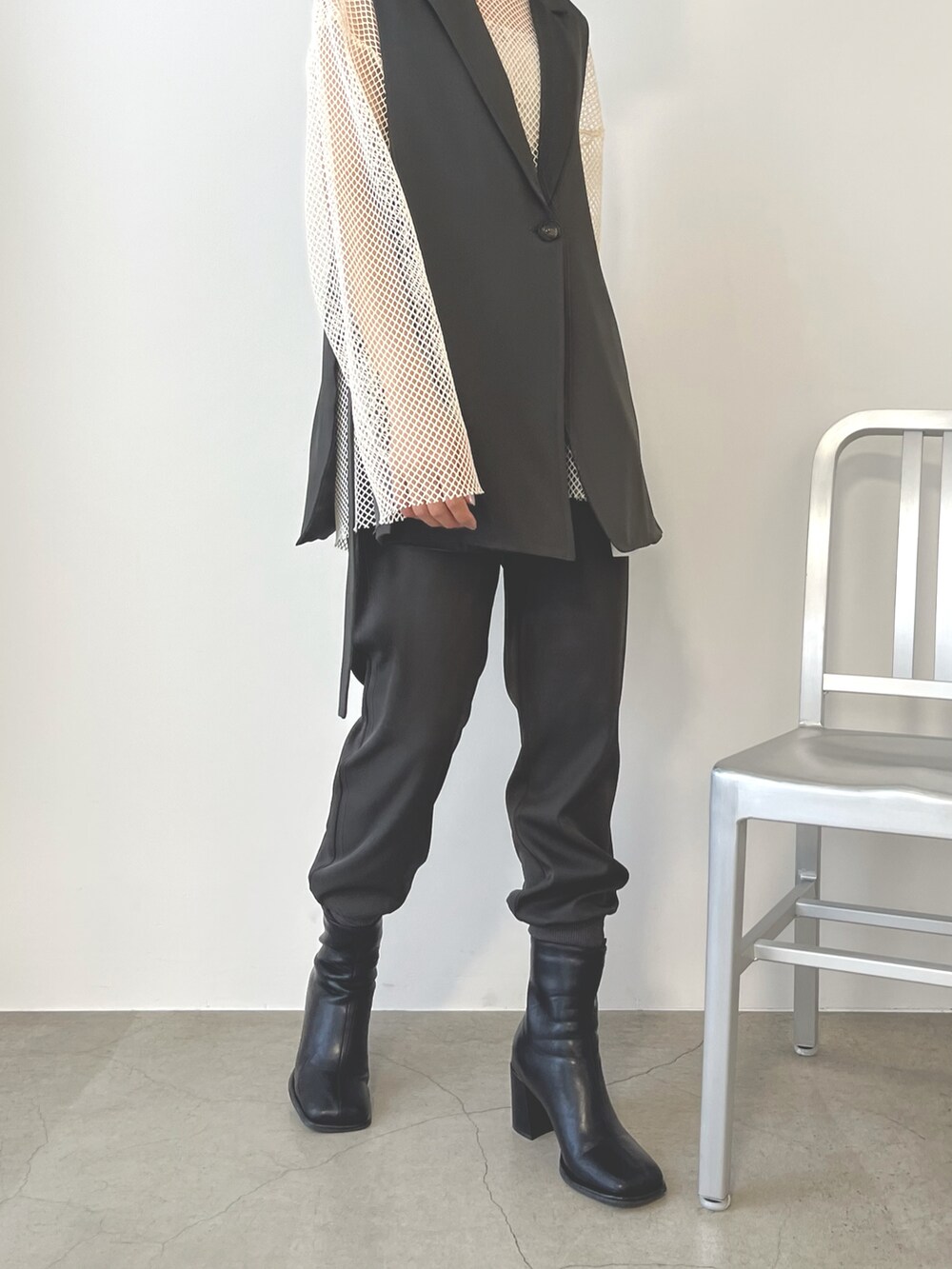 グレー系のスウェットパンツ、ブラック系のブーツ、ホワイト系のニット/セーターを着用したレディースの秋コーディネートの2枚目の写真