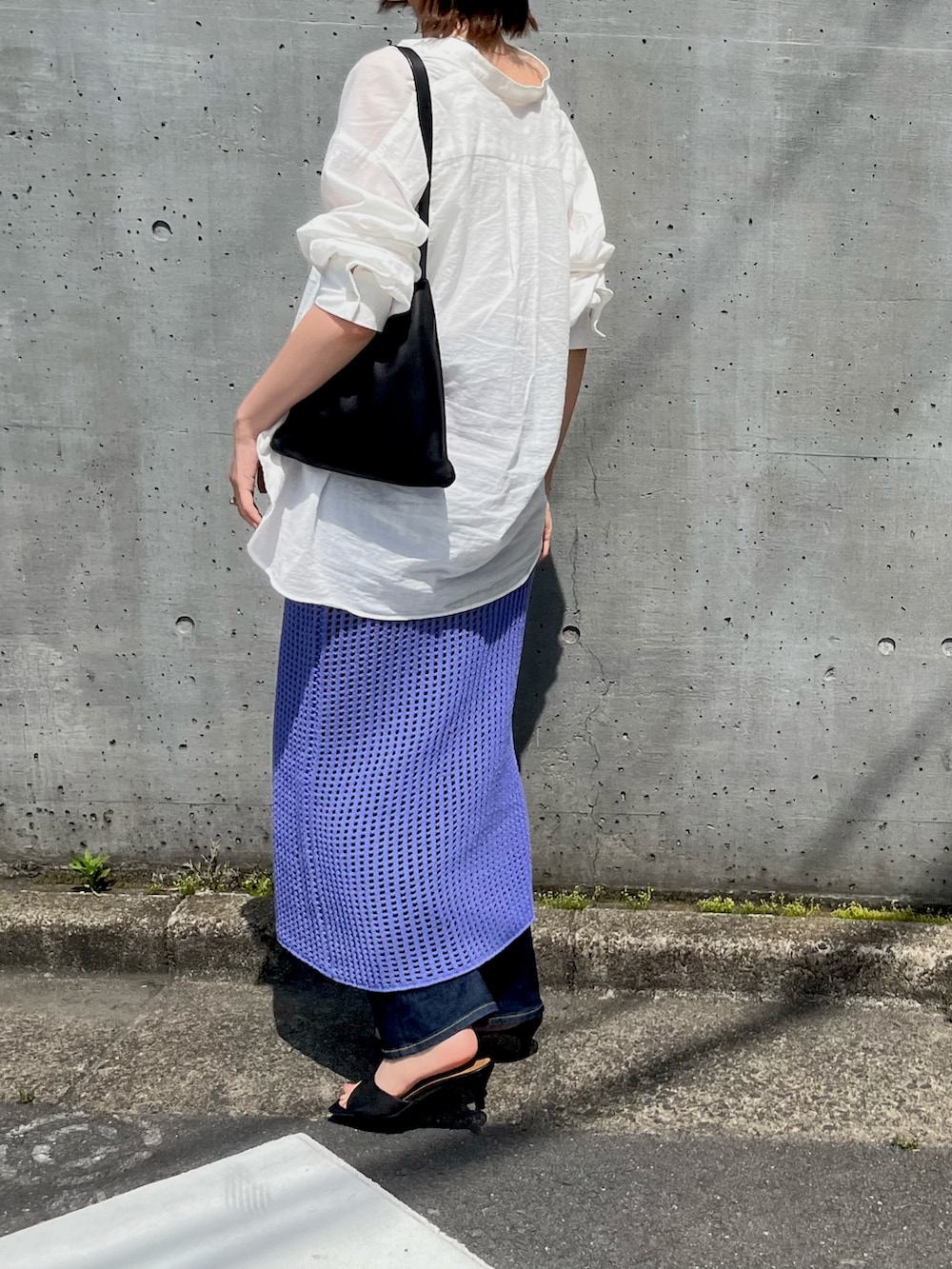ホワイト系のトップス、ブラック系のハンドバッグ、ブルー系のスカートを着用したレディースの春コーディネートの2枚目の写真