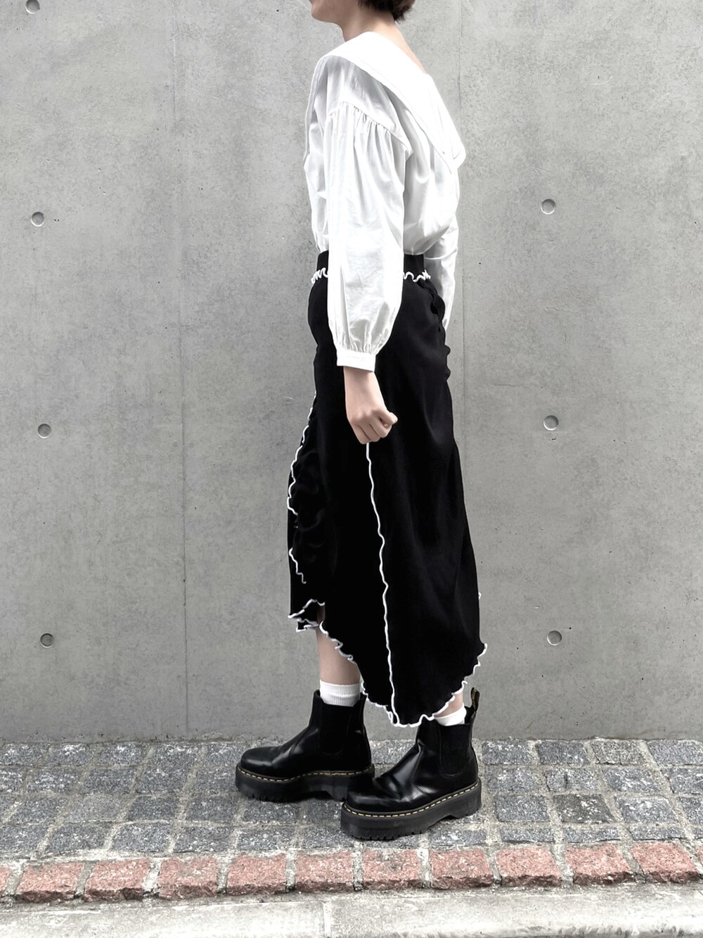 ベージュ系のシャツ/ブラウス、ブラック系のスカート、ブラック系のブーツを着用したレディースの春コーディネートの2枚目の写真