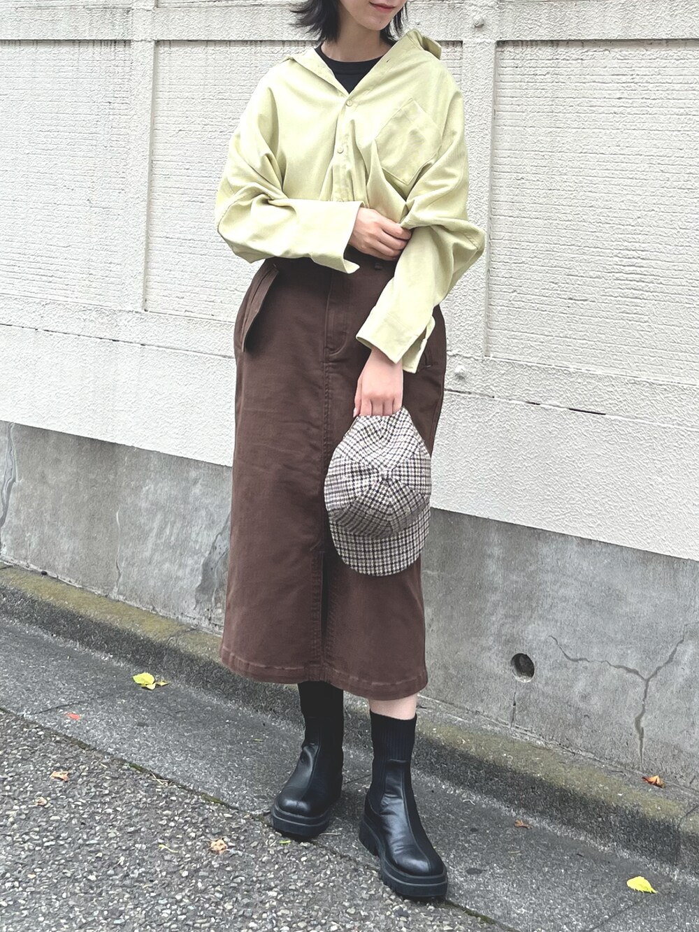 ブラック系のTシャツ/カットソー、イエロー系のシャツワンピース、ブラウン系のスカートを着用したレディースの秋コーディネートの2枚目の写真