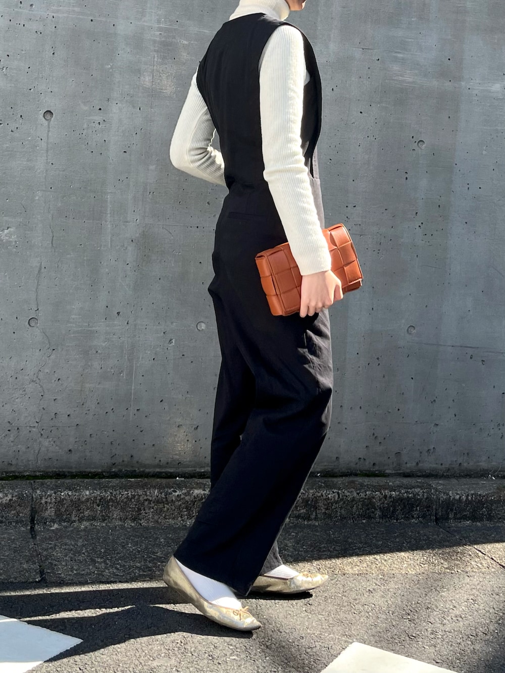 ゴールド系のシューズ、ブラック系のつなぎ/オールインワン、ホワイト系のニット/セーターを着用したレディースの春コーディネートの2枚目の写真