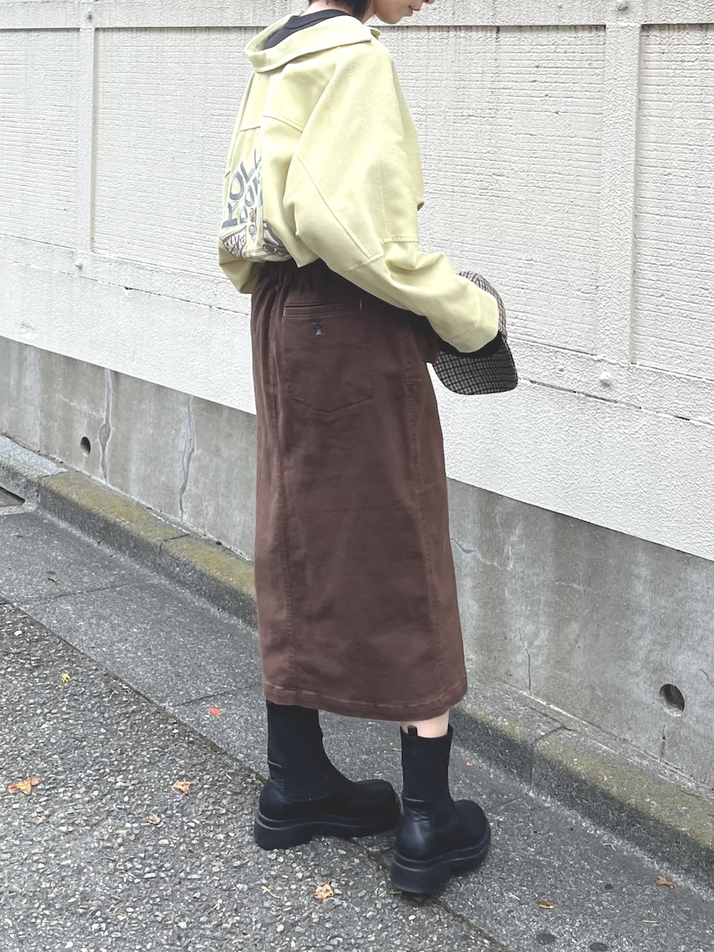ブラック系のTシャツ/カットソー、イエロー系のシャツワンピース、ブラウン系のスカートを着用したレディースの秋コーディネートの3枚目の写真