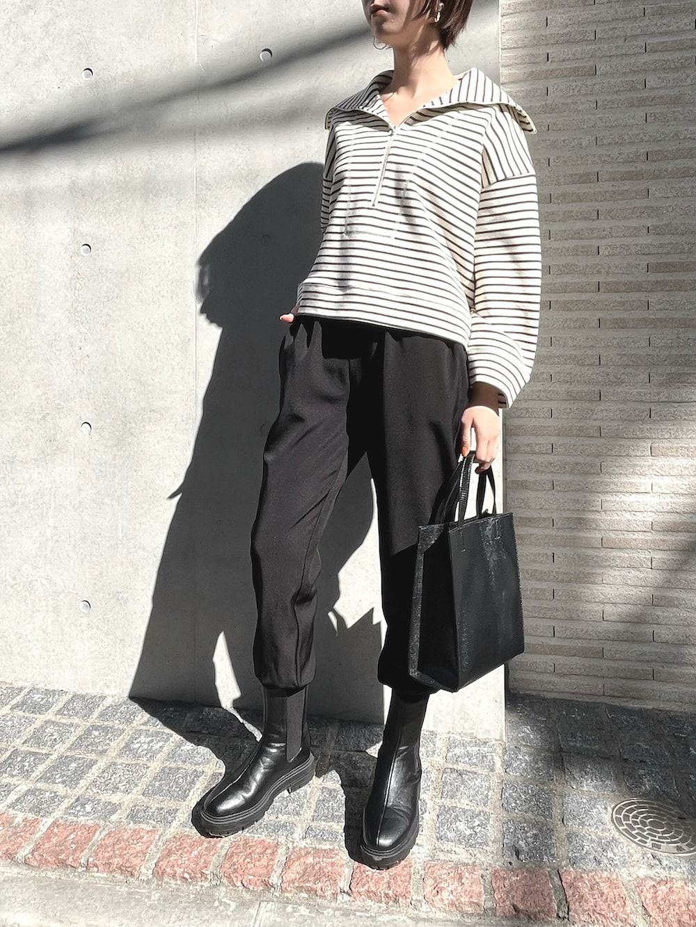 ブラック系のブーツ、ホワイト系のTシャツ/カットソー、ブラック系のスウェットパンツを着用したレディースの冬コーディネートの2枚目の写真