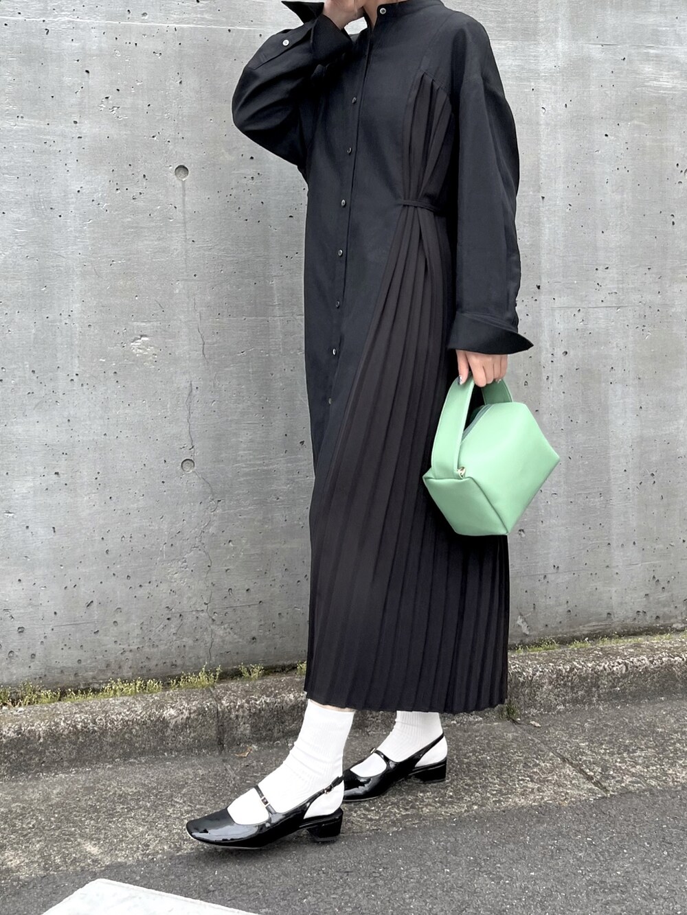 ブラック系のパンプス、ブラック系のワンピース/ドレス、グリーン系のショルダーバッグを着用したレディースの夏コーディネートの2枚目の写真