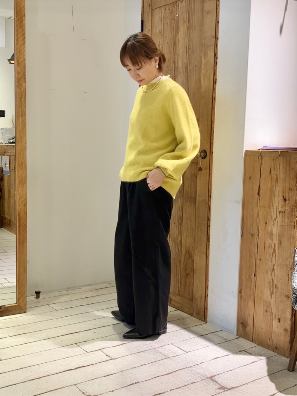 イエロー系のニット/セーター、ブラック系のスラックスを着用したレディースの秋コーディネートの2枚目の写真
