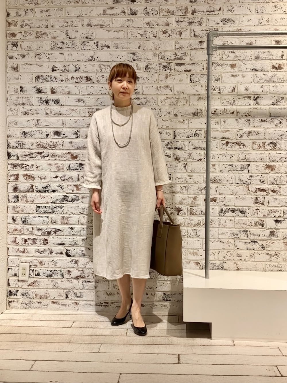 ホワイト系のワンピース、ベージュ系のショルダーバッグを着用したレディースの春コーディネートの3枚目の写真