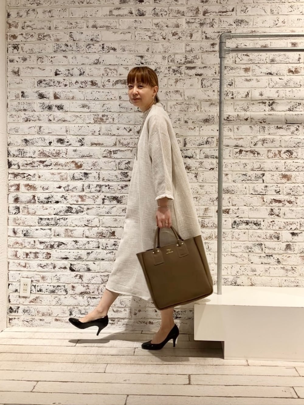 ホワイト系のワンピース、ベージュ系のショルダーバッグを着用したレディースの春コーディネートの5枚目の写真