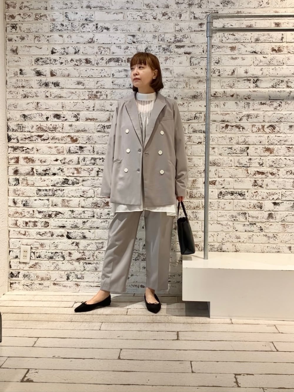 ホワイト系のシャツ/ブラウス、グレー系のテーラードジャケット、ベージュ系のスラックスを着用したレディースの冬コーディネートの3枚目の写真