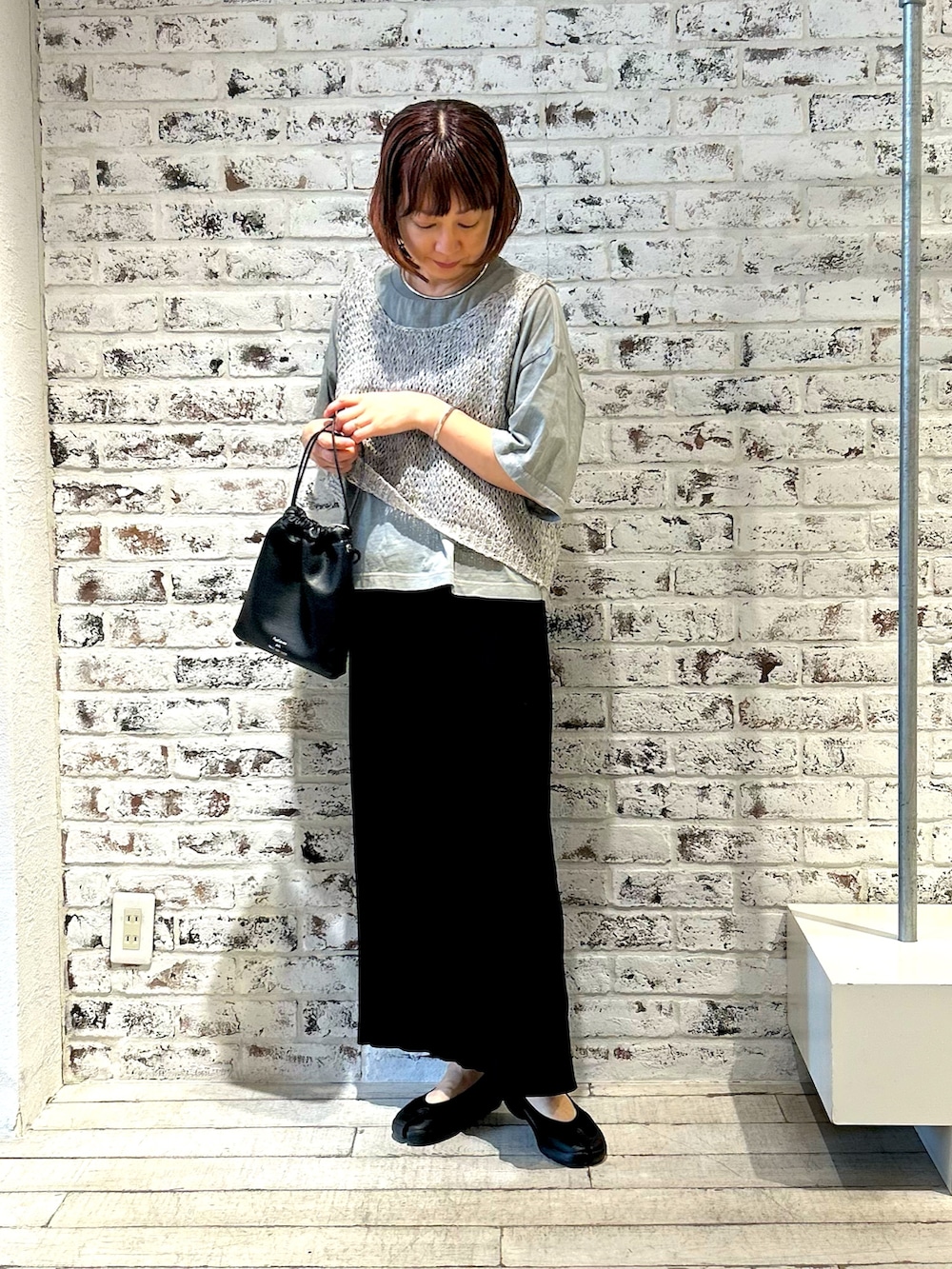 ホワイト系のベスト、ブラック系のスカート、グレー系のTシャツ/カットソーを着用したレディースの夏コーディネートの3枚目の写真